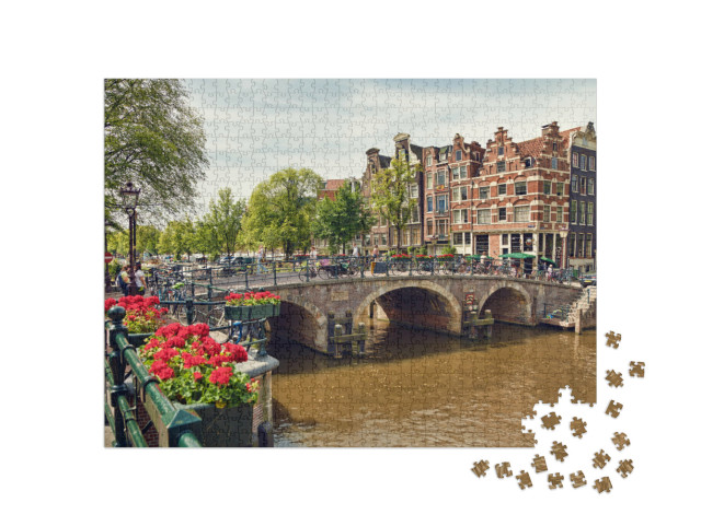 Puzzel 1000 stukjes „Drievoudige boogbrug in Amsterdam met geraniumbloesems tussen de grachten“