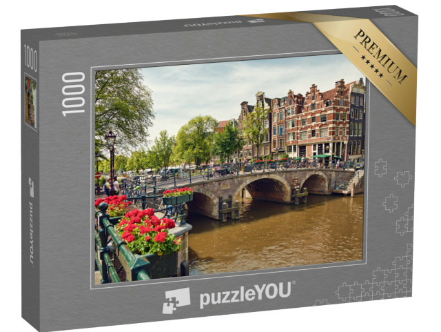 Puzzel 1000 stukjes „Drievoudige boogbrug in Amsterdam met geraniumbloesems tussen de grachten“